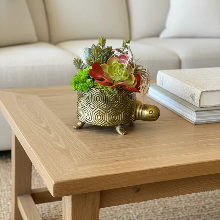 Decorative turtle planter with flowers on a wooden coffee table in a living room.